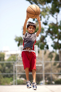 年轻篮球运动员在投时高空跳跃图片