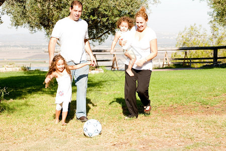 家长们和绿地上的孩子玩橄榄球图片