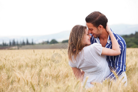 在草原上笑着彼此微的年轻夫妇图片
