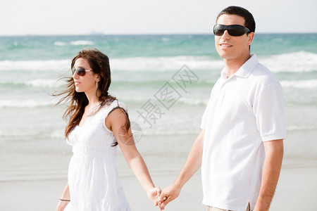 年轻夫妇手牵在海滩上走门外图片