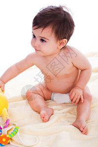 坐在黄色毛巾上带着玩具的托德人图片