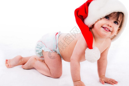 婴儿在白色背景中爬满了圣塔帽的婴儿图片