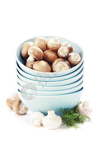 把碗和新鲜蘑菇堆在白色上图片