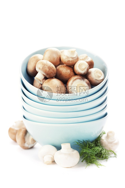 把碗和新鲜蘑菇堆在白色上图片