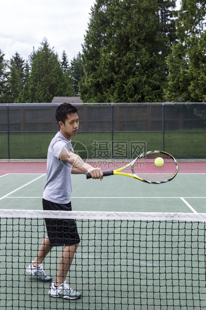 亚裔年轻人在户外网球场使用背手排图片