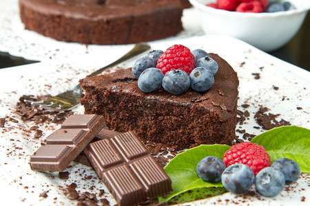 巧克力蛋糕白色盘子和黑背景上鲜莓果图片