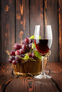 酒杯和葡萄在木制背景的篮子里图片