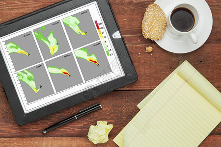用计算机模型拟烟羽流在数字平板电脑上用咖啡杯和笔记本查看图表图片