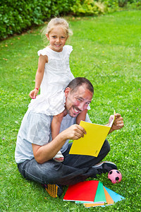 在花园的草地上父亲念书给女儿图片
