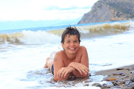 泼水男孩快乐笑的男孩十二岁在海边的背景