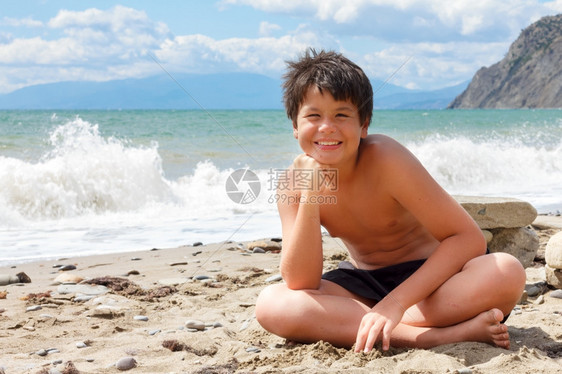 快乐笑的男孩12坐在海边的图片
