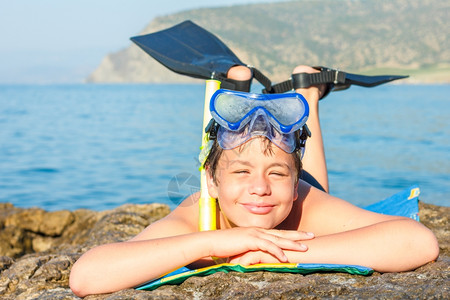 笑的十二岁男孩在海边戴着潜水面具和鳍图片