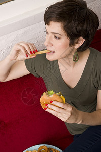 女人一边吃薯条芝士汉堡图片