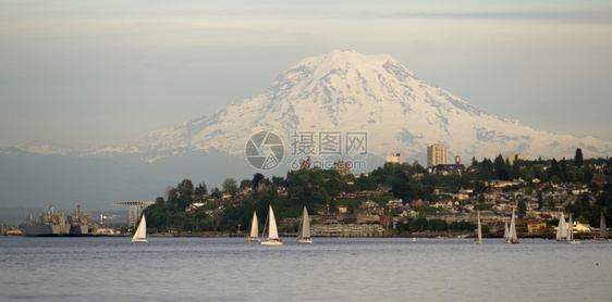 Rainier山在北塔科马和Ruston河滨水域上空大隆重的浮船和帆图片