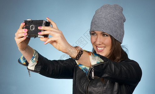 在BeanieCap的有吸引力女士用摄像头拍她自己的一张照片图片