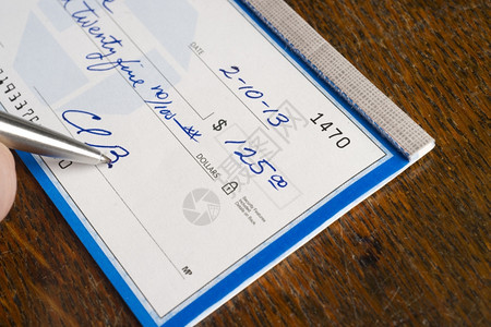 在办公桌顶端手签支票纸付款背景图片