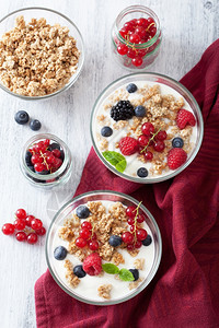 台布上的玻璃碗里含酸奶和浆果的健康早餐图片