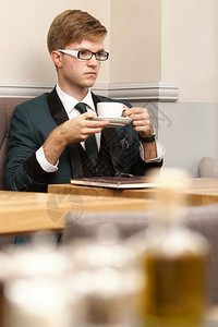 年轻英俊的时装模特放松思想喝咖啡在店等图片