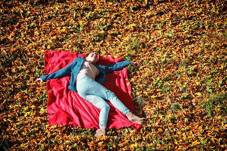 女孩躺在红色毯子上休息图片