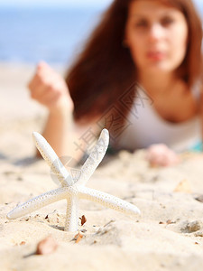 年青女子在海滨与星沙上一起渡暑假图片