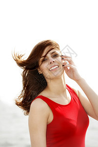 穿着红裙子的年轻女在码头早晨风吹着发暑假图片