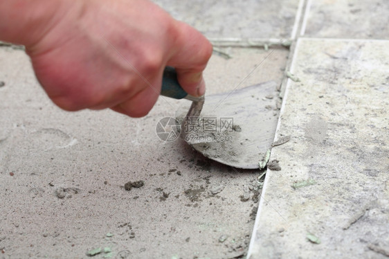 建筑工人在家里铺砖瓦地板粘合瓷砖图片