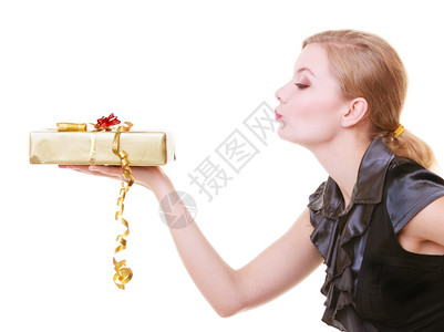 穿着黑裙子的金发美女拿着大金色圣诞礼物盒带丝年轻女人吹嘘吻假日孤立在白色上工作室中图片