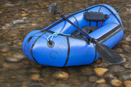 充气皮艇蓝色木船用于探险或赛的单人轻型木筏在浅河上挂有单艇桨背景