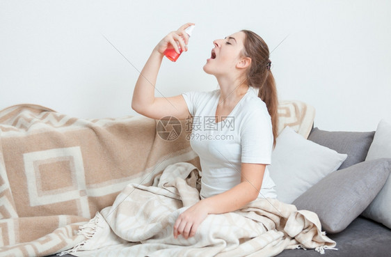 躺在床上并使用喉喷雾剂的生病妇女图片