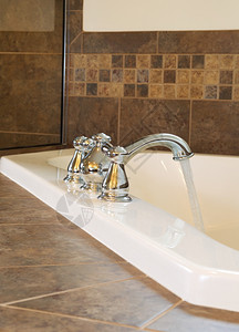垂直照片铬水龙头自来用在主浴室浸泡缸的垂直照片底有部分淋浴玻璃图片