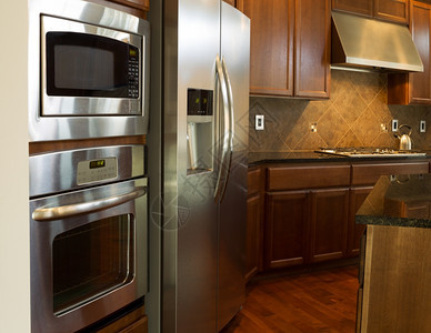 现代住宅厨房不锈钢器件的近照片上面有石质柜顶樱桃木子有硬地板图片
