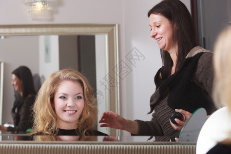 头发理师的金卷女孩型师和客户的发型师美容院的年轻女子发型图片