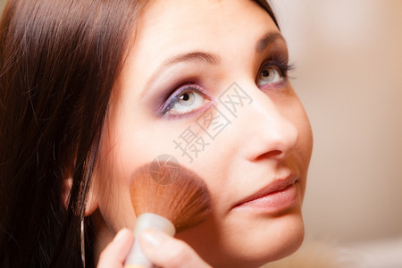 女美貌化妆师在检查其客户年轻女时用刷粉或草药施化妆师图片