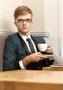 年轻英俊的时装模特放松思想喝咖啡在店等图片