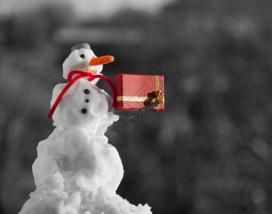 穿着蓝色螺丝顶上的小快乐雪人戴着帽子红围巾还有露天的叉子圣诞礼物盒冬季节特制模糊的背景图片