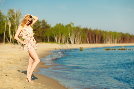 渡假穿暑期礼服的女孩和太阳镜站在空旷的海滩上年轻女人在海边放松夏天图片