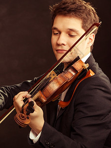 年轻优雅的小提琴家手玩黑色小提琴古典音乐演播室拍摄图片