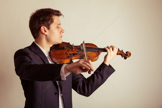 年轻优雅的小提琴家手在棕色古典音乐演播室拍小提琴图片