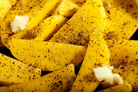 生土豆皮配有香料和黄油切片准备作为食物背景烤图片