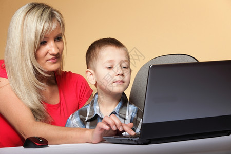 母亲帮助儿子一起完成电脑作业图片
