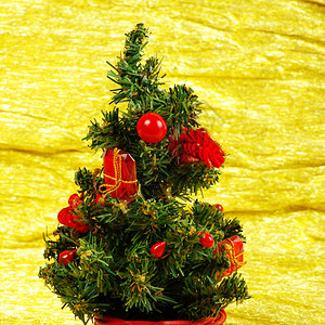 盛装的圣诞小树在金色背景和礼物的圣诞树上图片