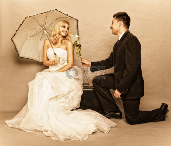 结婚日浪漫已夫妇金发新娘的肖像配着雨伞和美新郎的给女孩送玫瑰图片