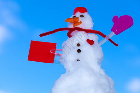 穿着红围巾的情人节小雪外出有纸短信心冬季节情人39日蓝天背景图片