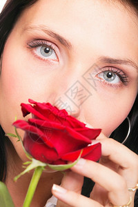 一位有魅力的年轻女子拿着红玫瑰的特写肖像图片