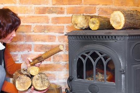 家里的冬天女人在壁炉上多放些木头图片