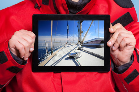男手握着游艇帆船的照片紧握着皮达的男手水们展示了屏幕平板电脑触摸梦想着游艇航行技术和游轮图片