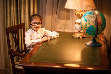 坐在书桌后面的眼镜上笑小女孩肖像图片