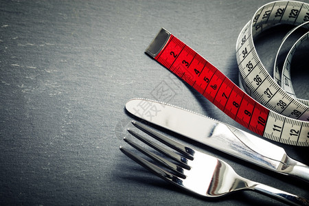 灰色背景的计量磁带刀叉和饮食概念图片