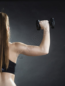身体健康的女孩身体健康的女人举起哑铃的重量做运动用哑铃锻炼训练肩部肌肉反视灰色背景图片