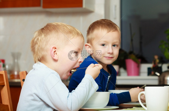 两个金发男孩子们在餐桌吃早餐图片